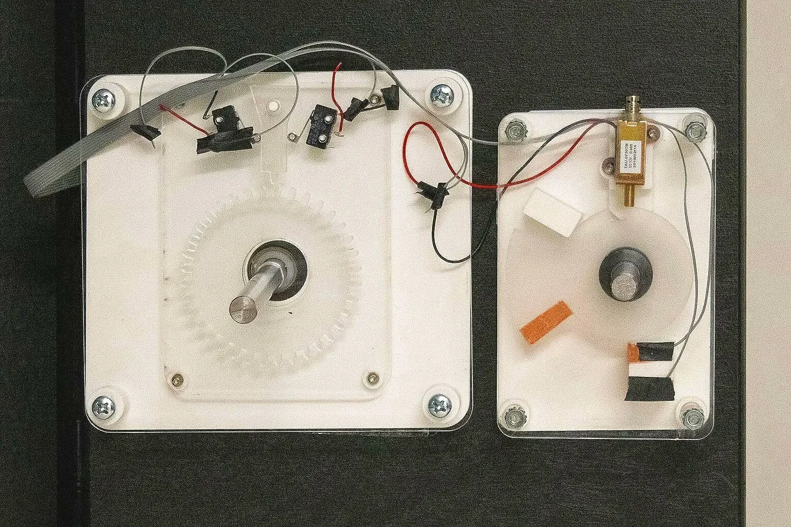 A printed gear and microswitches on one acrylic panel, with a solenoid on a second