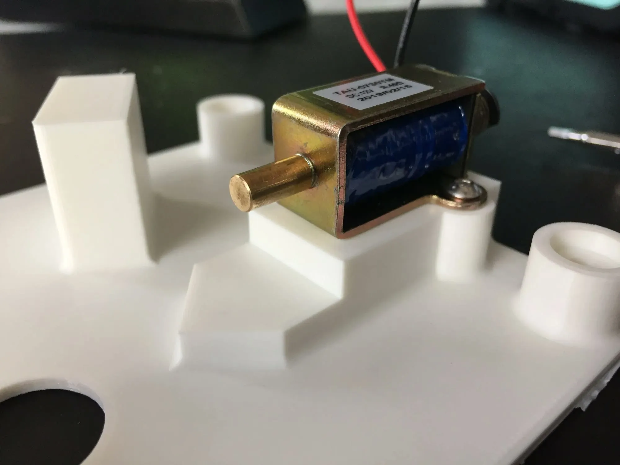 A solenoid seated in white 3D-printed mounts